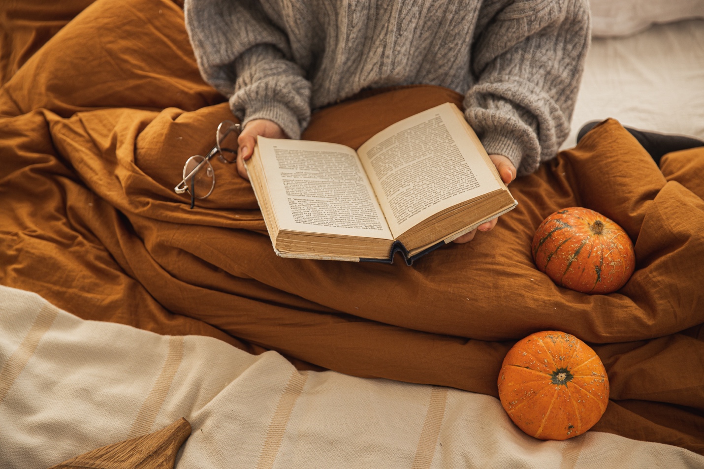 woman reading with blankets and pumpkins